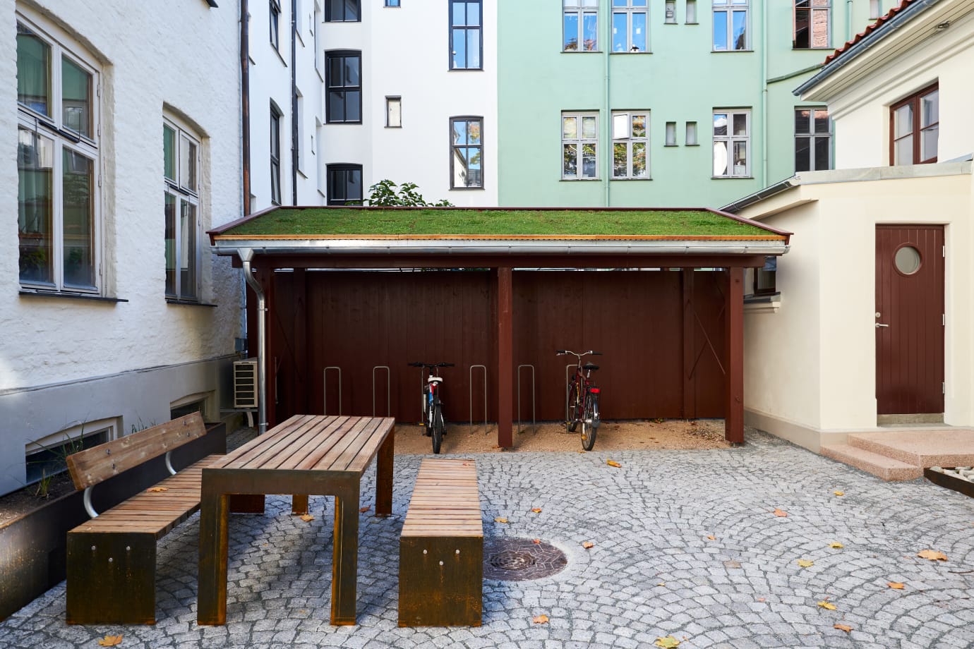 Bakgården i Bergsliens gate har blitt istandsatt med bedre overvannshåndtering og nytt uttrykk med vakkert lagt brostein, planter, benker og bord, samt et sykkel- og vognskur med grønt tak.